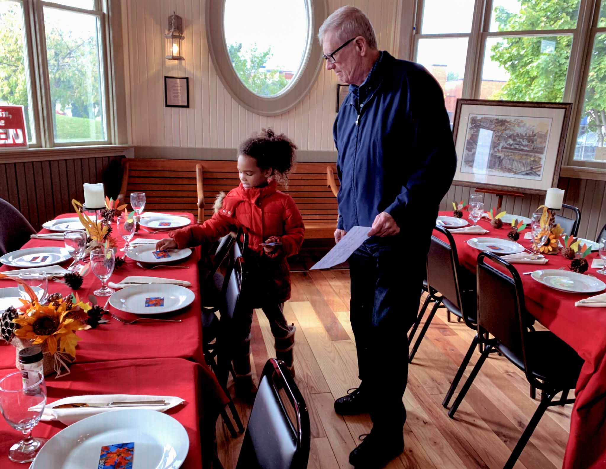 A Freeman Station volunteer and kid, set up the dining room inside Freeman Station.